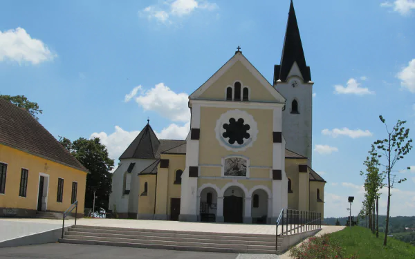 Religious church with tall steeple and rose window on a sunlit plaza under blue sky — 4K Ultra HD PC desktop wallpaper background.
