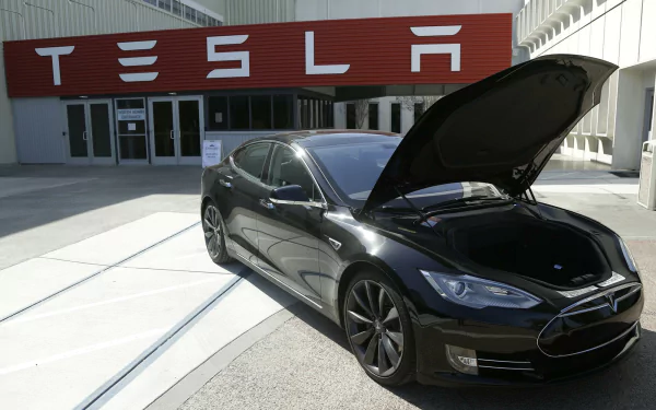 A Tesla electric car with an open hood in front of a Tesla building, as a HD desktop wallpaper and background.