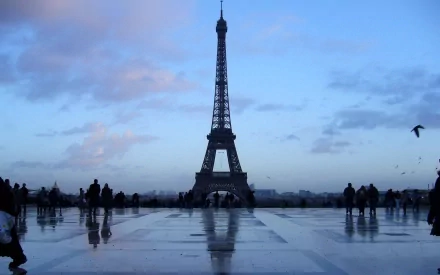 A scenic view of the Eiffel Tower under a twilight sky, surrounded by silhouettes of people, captured in high definition for a striking desktop wallpaper and background.