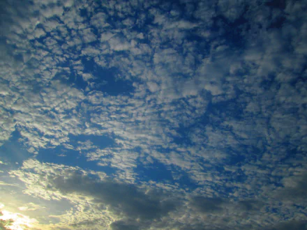 4K Ultra HD PC desktop background: textured, cloud-filled blue sky with scattered sunlight near the horizon, a serene nature scene.