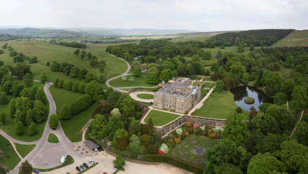 Aerial view of Lyme Park estate showcasing its man-made mansion and landscaped gardens, surrounded by lush greenery and winding roads in a high-definition desktop wallpaper.