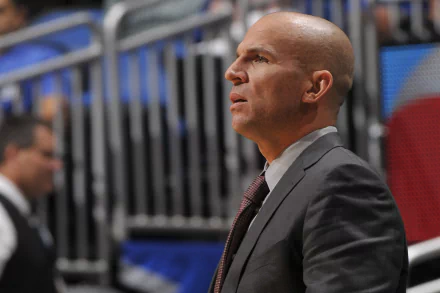 HD desktop wallpaper featuring a profile view of Jason Kidd in a suit, focused on the sidelines of a basketball court.