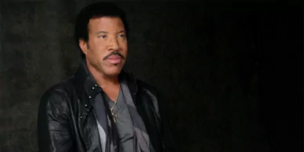 HD wallpaper of a man resembling Lionel Richie in a leather jacket against a dark background.