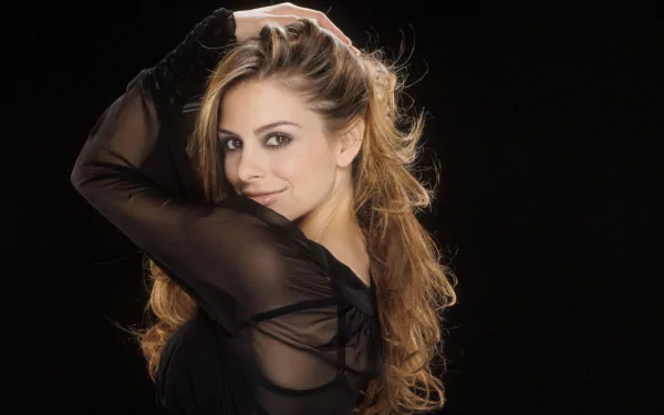 HD desktop wallpaper of American actress and celebrity Maria Menounos posing against a black background with long wavy hair and a sheer black top.