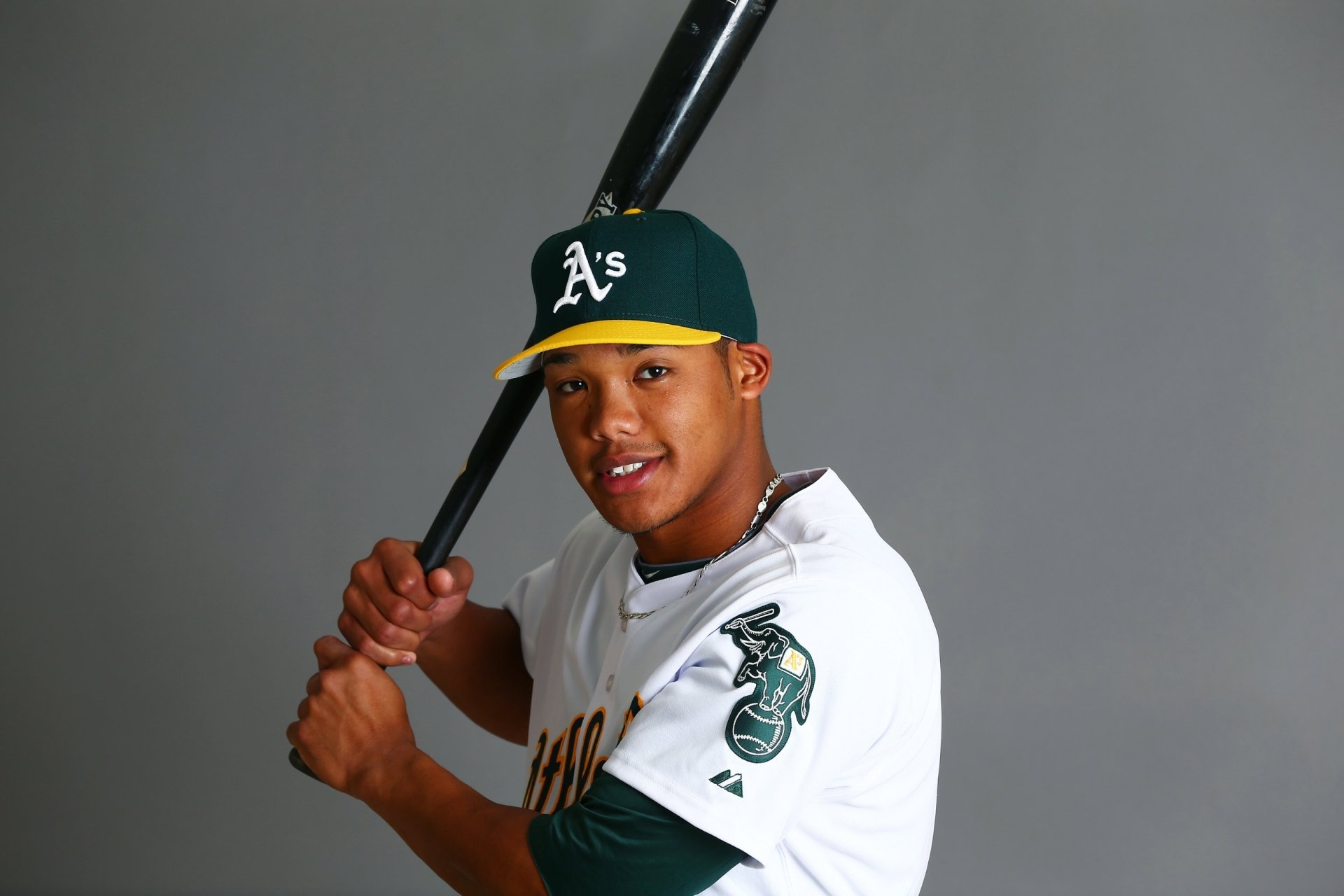 HD wallpaper featuring a player in an Oakland Athletics uniform holding a baseball bat, set against a grey background.