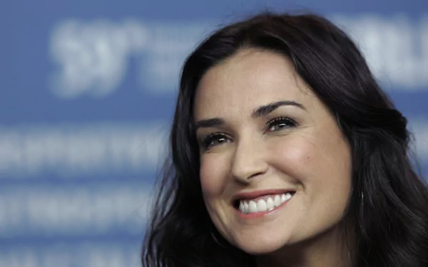 HD desktop wallpaper featuring a close-up of American actress and celebrity Demi Moore smiling against a blurred blue background.