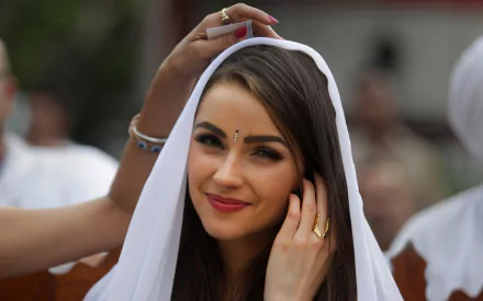 American celebrity and model Olivia Culpo smiles gently, adjusting a white headscarf in this HD PC desktop wallpaper and background image.