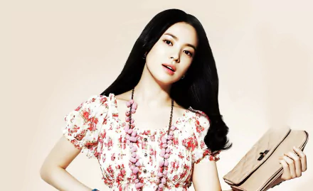 A stunning HD desktop wallpaper featuring Korean celebrity Song Hye Kyo, exuding elegance with her floral dress and stylish accessories, set against a soft background.