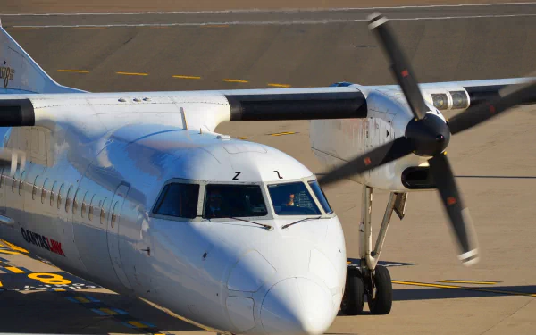 A close-up view of a QantasLink Bombardier Dash 8 Q315 aircraft on the tarmac, showcasing its twin propellers and sleek design in high definition.