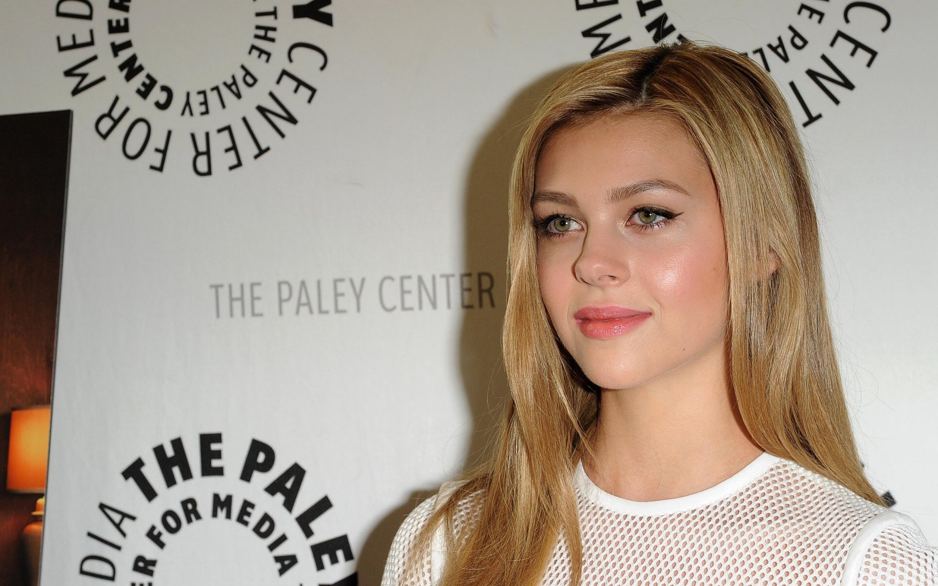 American actress Nicola Peltz poses at a media event, featured in an HD PC desktop wallpaper and background.
