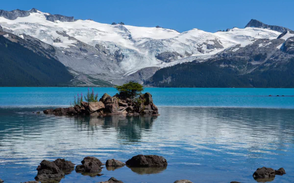 A stunning HD desktop wallpaper of Garibaldi Lake featuring turquoise waters, rocky islets, and snow-capped mountains under a clear blue sky.