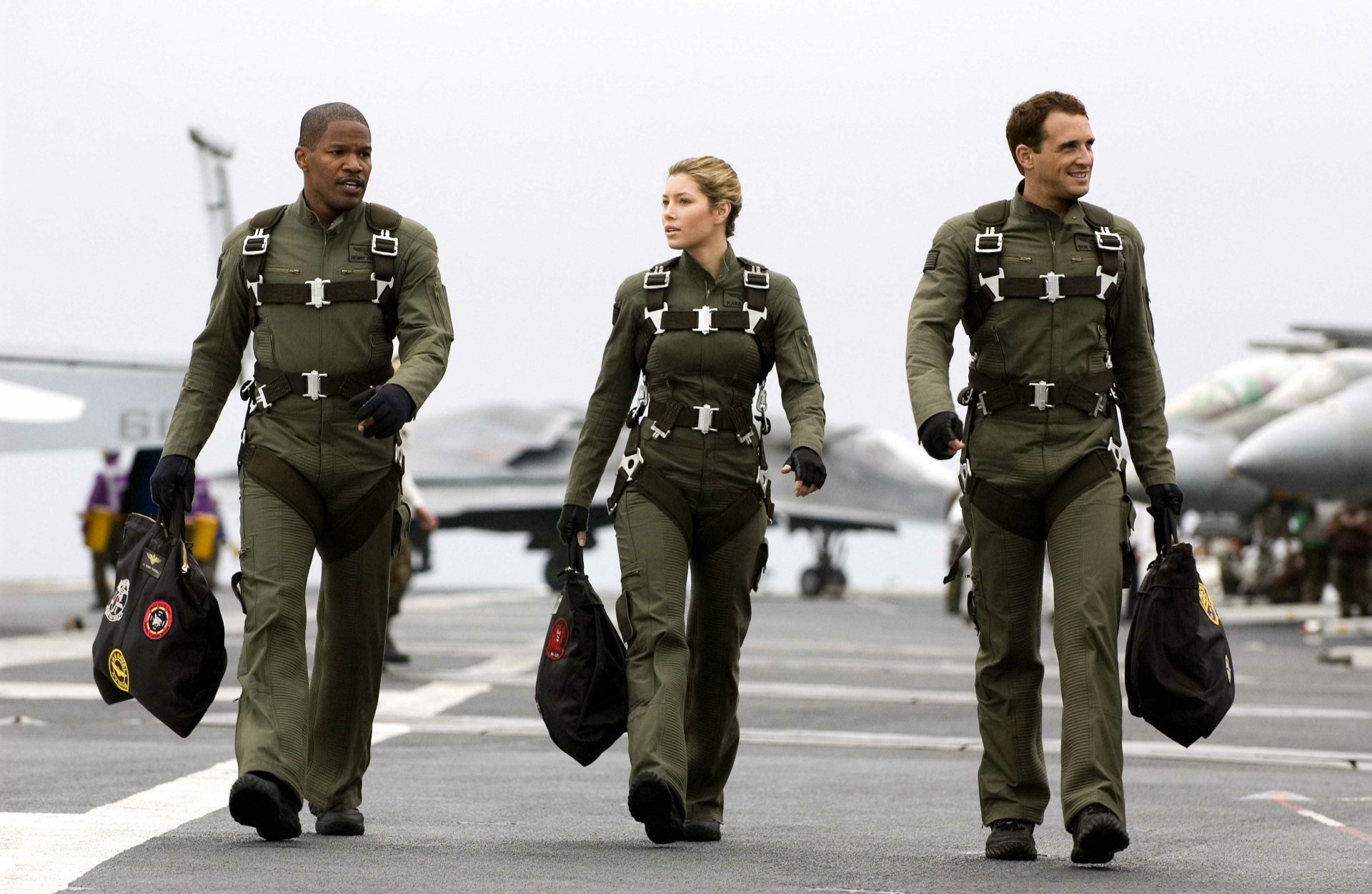 Three pilots in flight suits walk down a carrier deck with fighter jets behind them — Stealth (2005) movie image, 4K Ultra HD PC Desktop Wallpaper and Background.