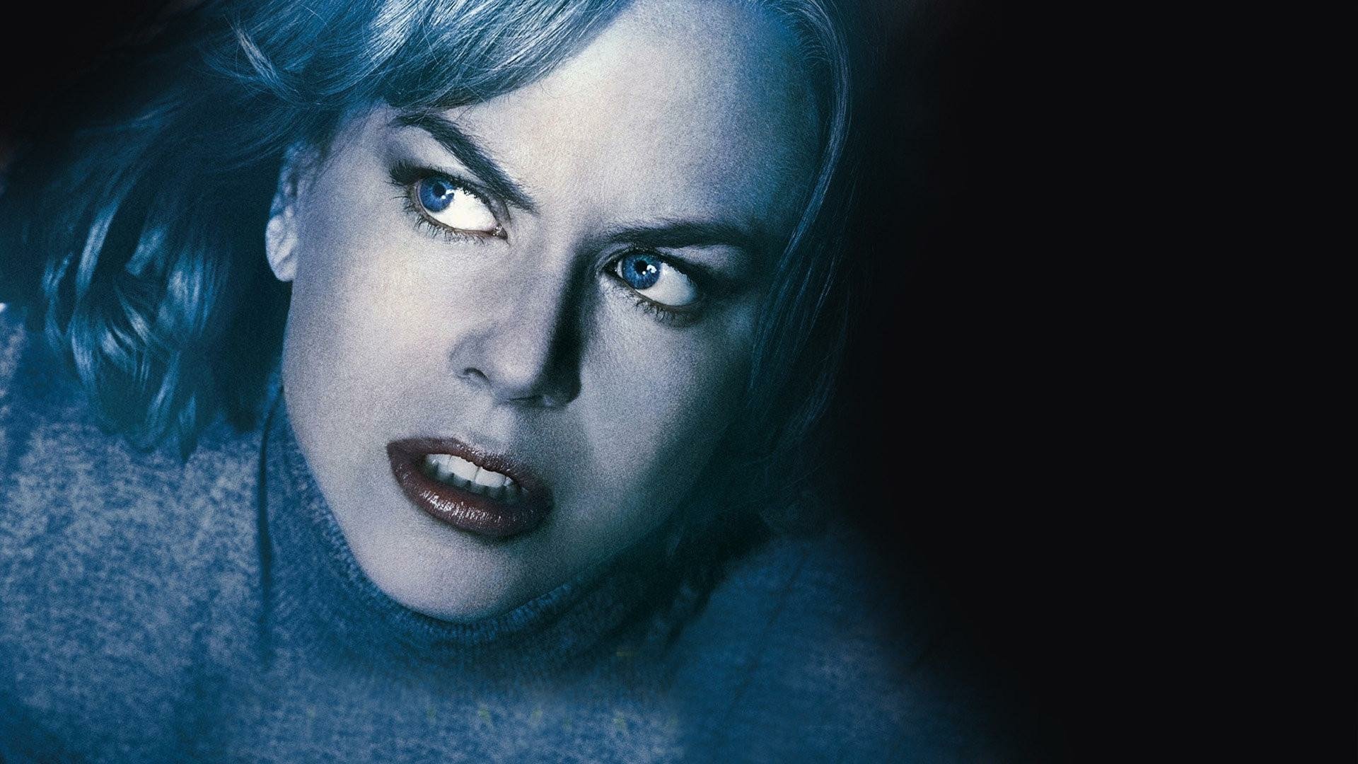 HD PC desktop wallpaper for the movie The Invasion: close-up of a pale, intense woman with blue-tinted hair and a piercing gaze against a dark background.
