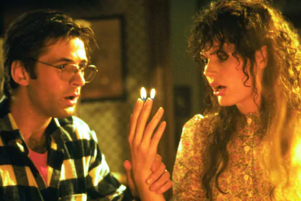 HD PC desktop wallpaper of a Beetlejuice movie scene: two startled characters examine tiny flames held between their fingers in a dim, patterned room.