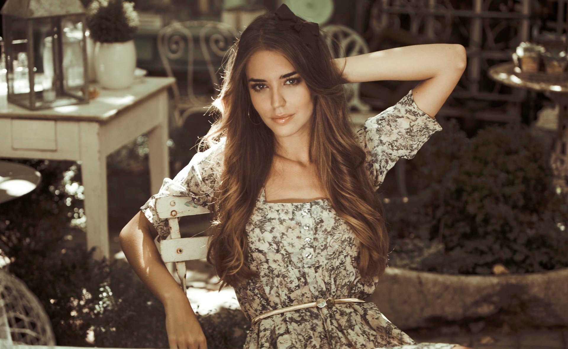 HD desktop wallpaper of Spanish woman Clara Alonso posing outdoors in a floral dress with soft sunlight enhancing the natural, serene setting.