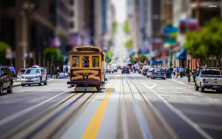 A vibrant HD desktop wallpaper featuring a tilt-shift photography view of a San Francisco cable car moving along a busy city street.
