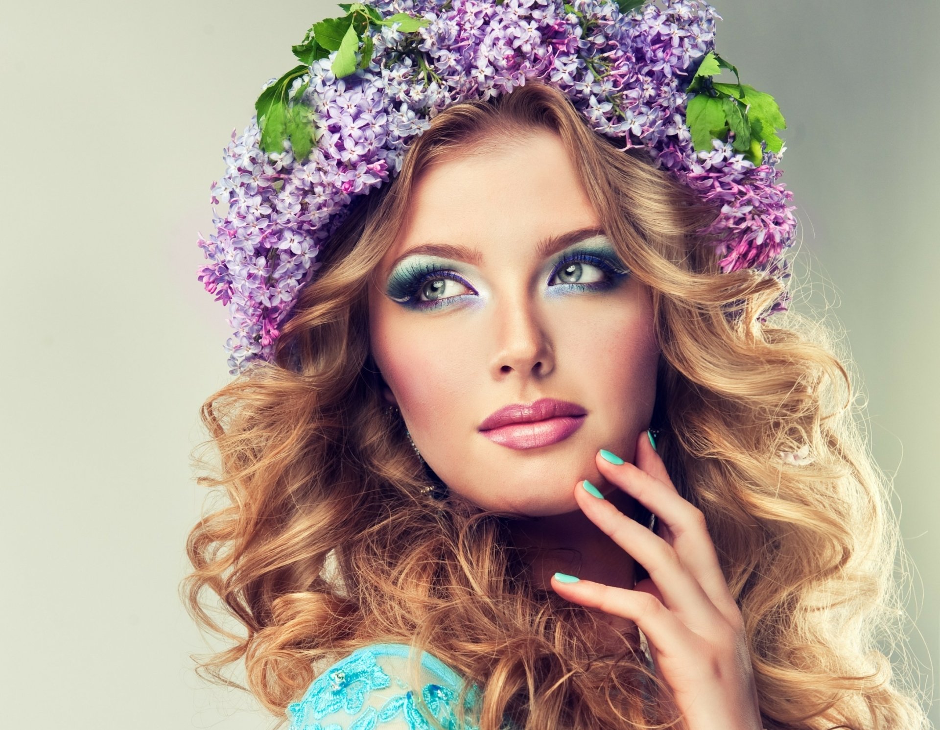 A woman with flowing curls adorned in a lilac wreath gazes thoughtfully, showcasing a fresh makeup look. This vibrant image serves as an eye-catching HD desktop wallpaper.