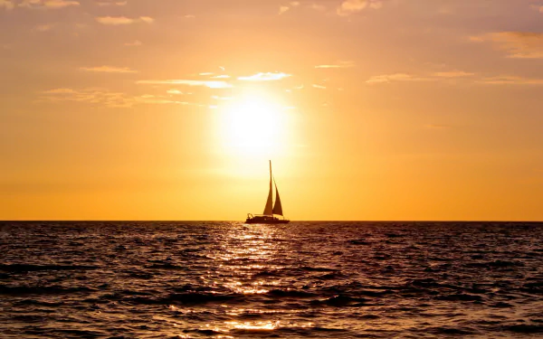A serene scene of a sailboat gliding across the sea at sunset, with vibrant orange skies reflecting on the water. A stunning 4K Ultra HD wallpaper for your desktop.