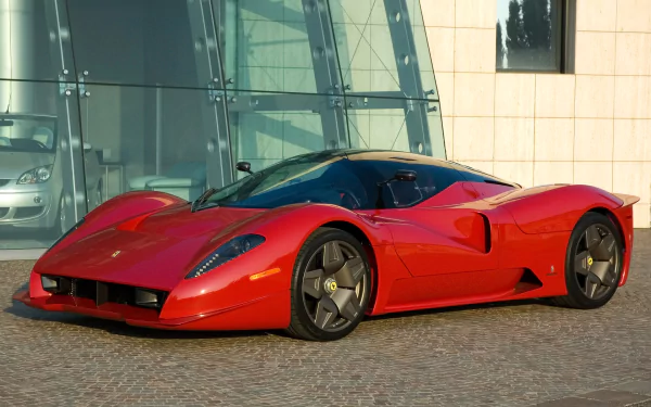HD desktop wallpaper featuring a sleek red Ferrari Pininfarina P4/5 Concept parked on a modern urban street with glass and stone buildings in the background.