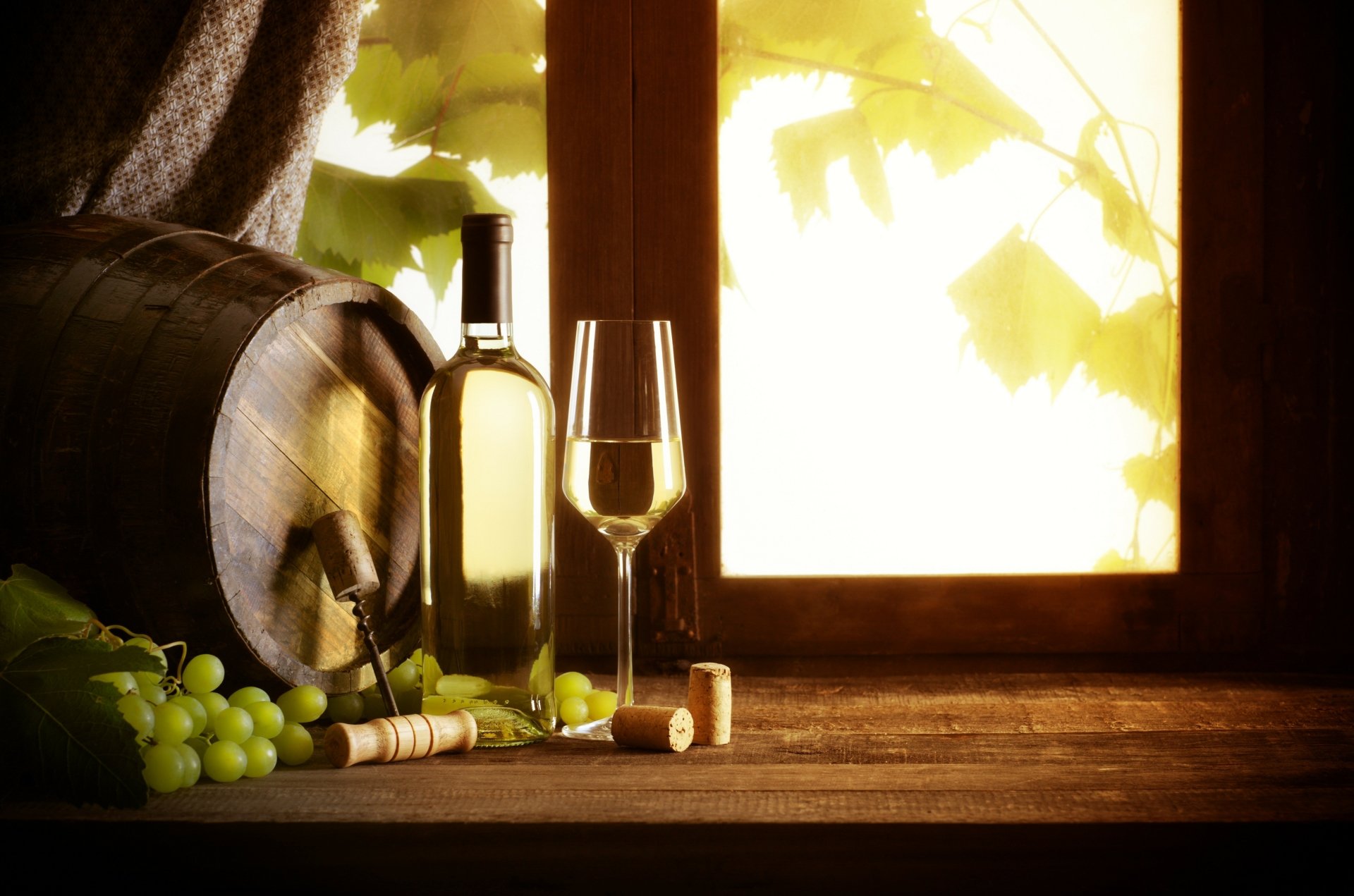 4K Ultra HD desktop wallpaper featuring a rustic scene with green grapes, a wine barrel, a bottle of white wine, and a filled wine glass by a sunlit window.