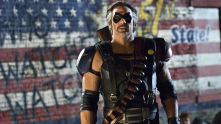 HD PC desktop wallpaper from the Watchmen movie: a masked, armored vigilante wearing a bandolier stands before a weathered American flag, exuding gritty urban heroism.