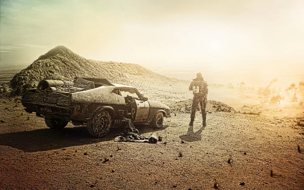 A desolate landscape features Max Rockatansky standing beside a battered car, evoking the intense atmosphere of Mad Max: Fury Road in this striking HD wallpaper.