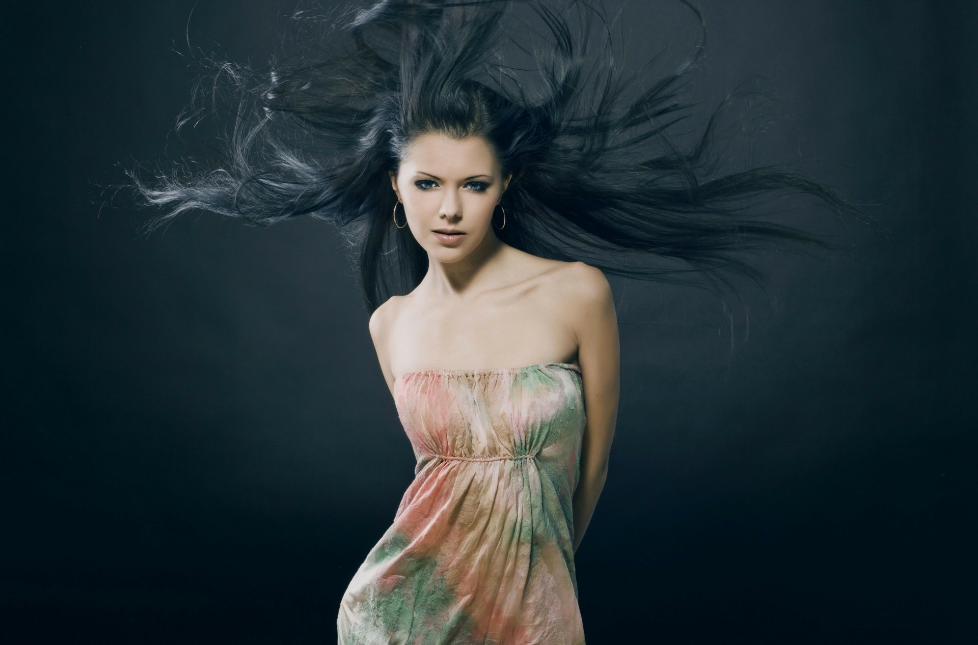 A striking 4K Ultra HD PC desktop wallpaper of a female model with flowing dark hair against a dark background, wearing a strapless, colorful dress.