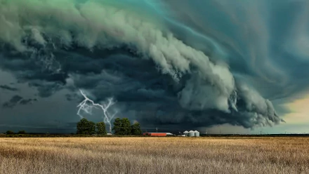 A dramatic sky filled with dark storm clouds and vivid lightning strikes, set above a vast field and a distant farm. This stunning image serves as a captivating HD desktop wallpaper.