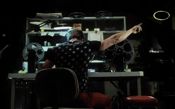 A HD desktop wallpaper and background from the movie Fight Club, featuring a character pointing at the ceiling while sitting at a cluttered desk in a dark room.