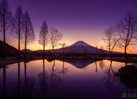 HD desktop wallpaper of Mount Fuji in Japan at sunset, with silhouetted trees reflecting on a still lake, showcasing serene natural beauty.