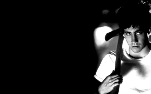 Black-and-white HD desktop wallpaper featuring Jake Gyllenhaal from the movie Donnie Darko, with a dark background and intense expression.