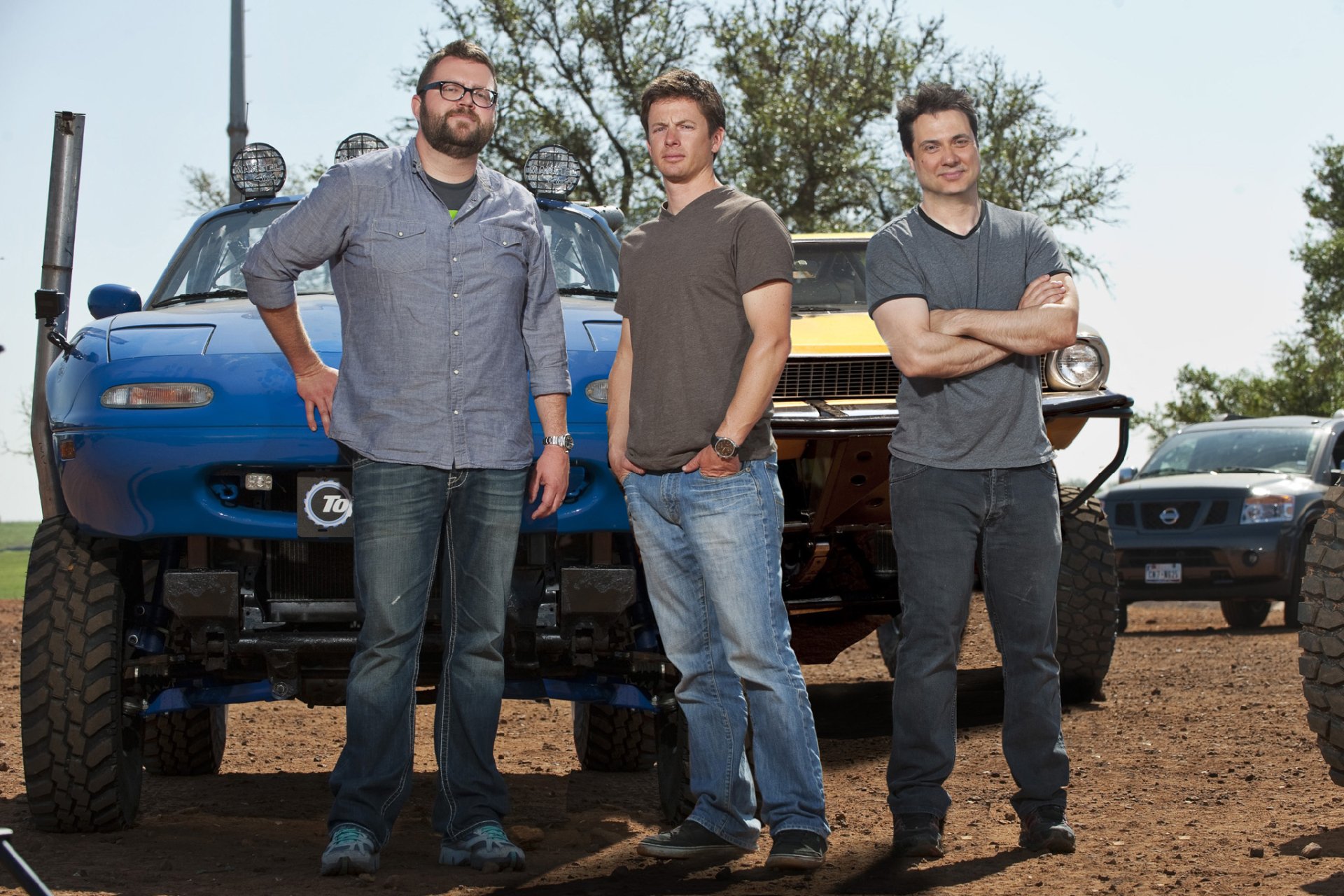 HD desktop wallpaper of three people from Top Gear standing in front of modified vehicles with a clear sky in the background.