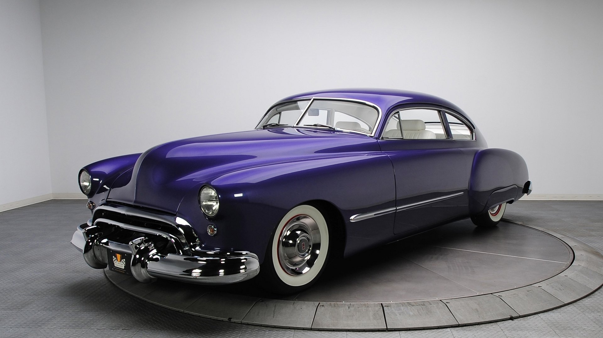 HD desktop wallpaper of a sleek purple Oldsmobile, showcasing its classic design and polished chrome details against a minimalist background.