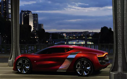 HD desktop wallpaper showcasing a sleek red Renault Dezir vehicle parked by a riverside with a city skyline at dusk.
