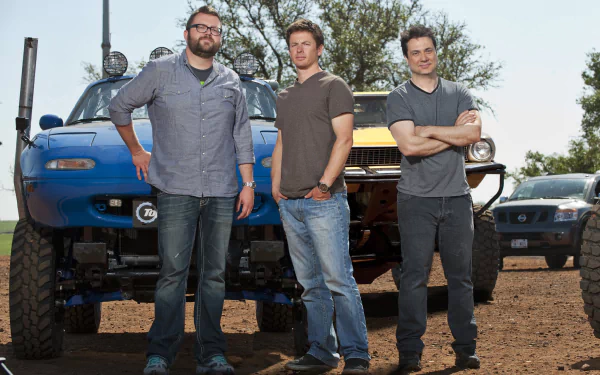 HD desktop wallpaper of three people from Top Gear standing in front of modified vehicles with a clear sky in the background.