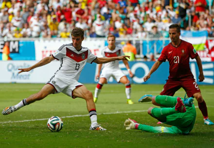 Thomas Müller dribbles past a goalkeeper during a dynamic soccer match between Germany and Portugal, capturing the intensity of sports in this HD desktop wallpaper.