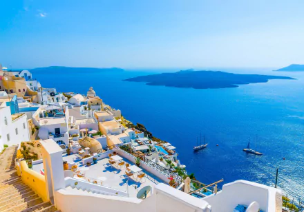 HD wallpaper of Santorini, Greece showcasing white-washed houses cascading down to the blue Aegean Sea, with a clear horizon and sunshine illuminating the serene island landscape in the background.