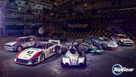 HD desktop wallpaper featuring Lotus, Ford, Porsche, and Lancia cars displayed in the Top Gear TV show garage with iconic racing liveries.