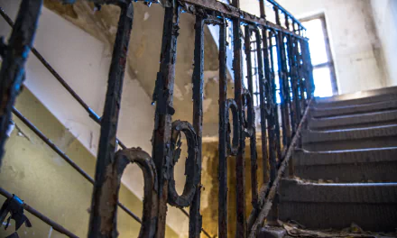 Rusted iron railing and crumbling concrete stairwell in an urban German ruin, HDR 5K Ultra HD desktop wallpaper/background.