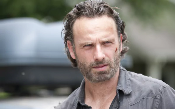 HD desktop wallpaper featuring a close-up of a character from the TV show The Walking Dead with a serious expression and outdoor background.