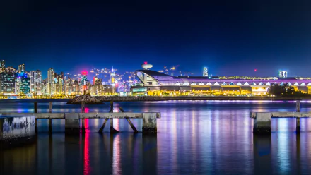 Victoria Harbour at night with illuminated Kai Tak area and Hong Kong skyline reflecting on calm waters, captured in stunning 4K Ultra HD clarity.