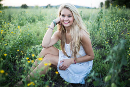 HD desktop wallpaper featuring a woman with a smile, sitting in a lush green field surrounded by wildflowers.