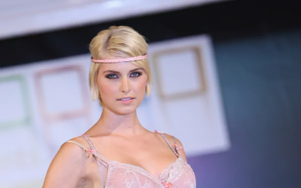 HD desktop wallpaper features German model Lena Gercke with blonde hair styled in a headband, wearing a delicate pink outfit against a blurred background.