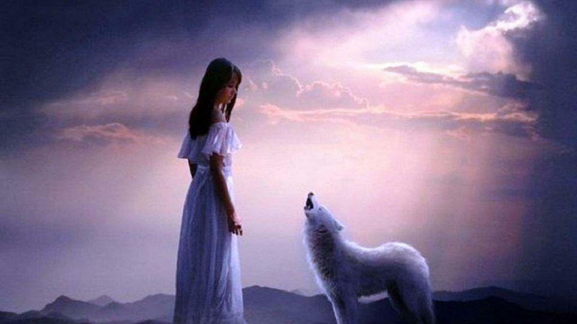 A serene HD desktop wallpaper showing a woman in a white dress standing beside a howling white wolf under a dramatic, cloudy sky.
