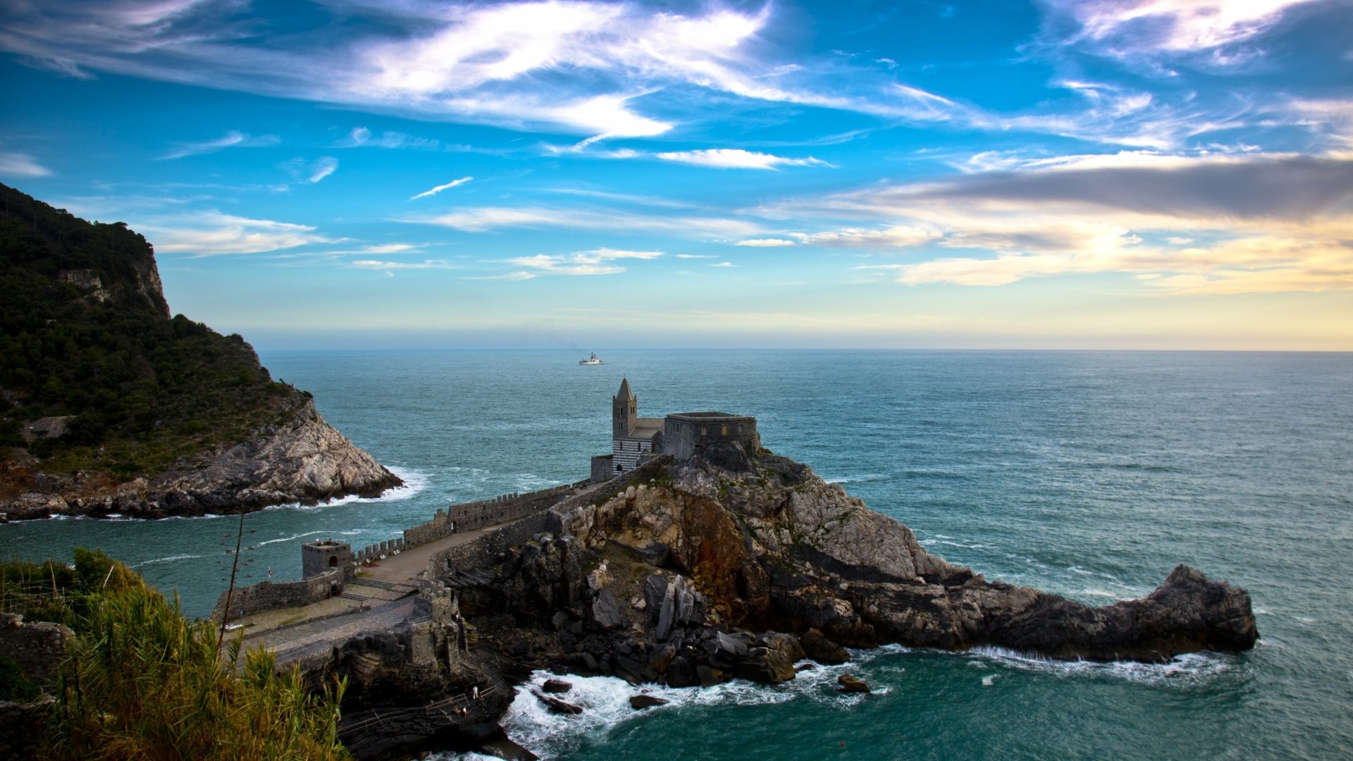 A man-made structure on a rocky peninsula extends into the sea under a vibrant sky at Porto Venere, captured in 4K Ultra HD for a PC desktop background.