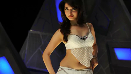 A glamorous Bollywood celebrity, Tamannaah Bhatia, poses in a stylish outfit against a modern backdrop, making it an eye-catching HD desktop wallpaper.