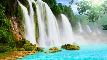 HD desktop wallpaper featuring a stunning nature scene with cascading waterfalls, lush green foliage, and turquoise water under a bright sky.