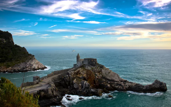 A man-made structure on a rocky peninsula extends into the sea under a vibrant sky at Porto Venere, captured in 4K Ultra HD for a PC desktop background.
