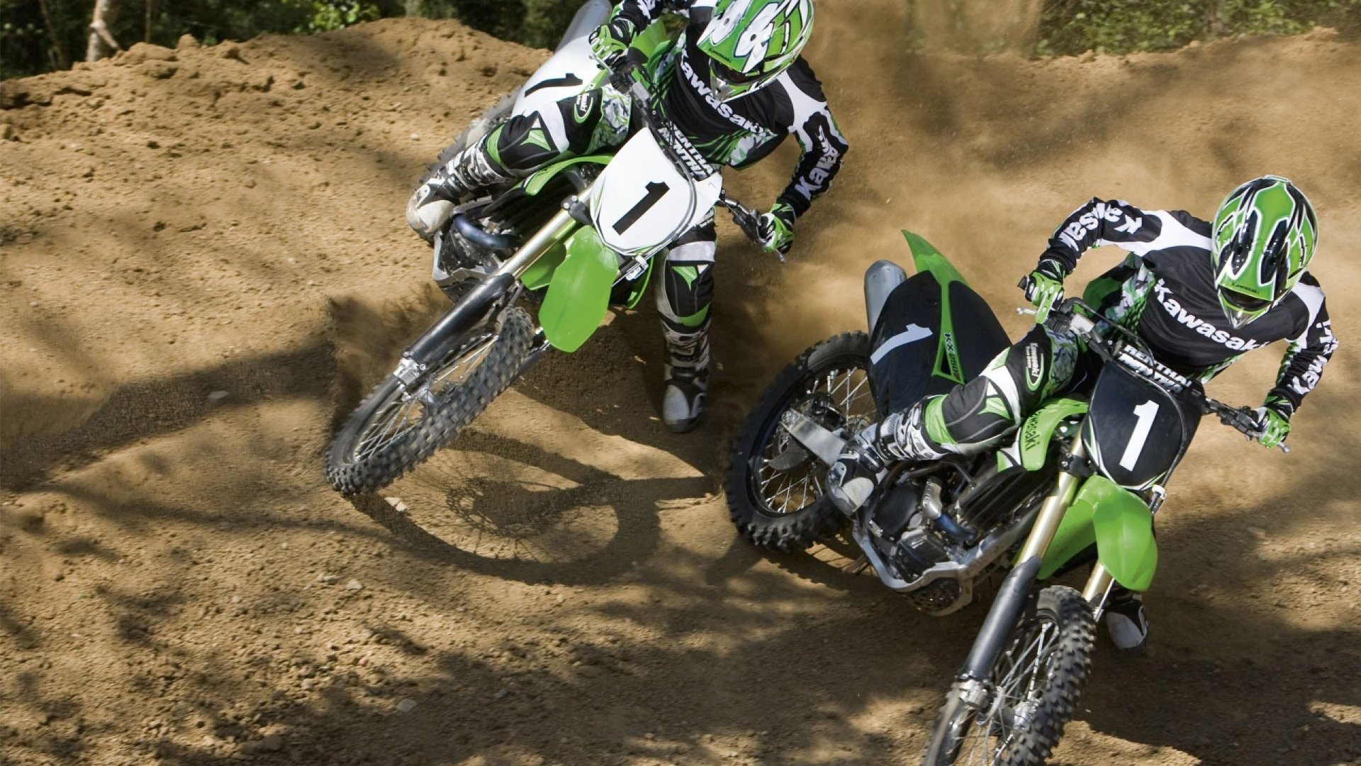 Two motocross riders compete on dirt trails, showcasing the thrill of sports in an HD desktop wallpaper background. Vivid details capture the intensity of the race.