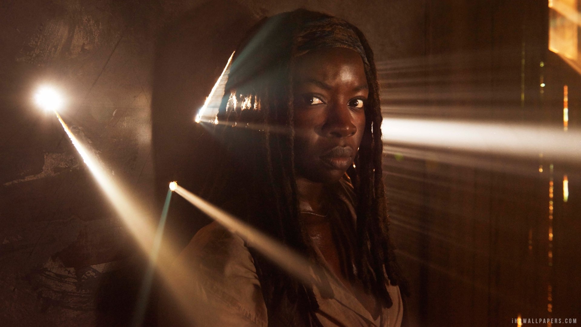 A dramatic scene from the TV show The Walking Dead, featuring a woman with long hair illuminated by beams of light, creating a mysterious and intense atmosphere.